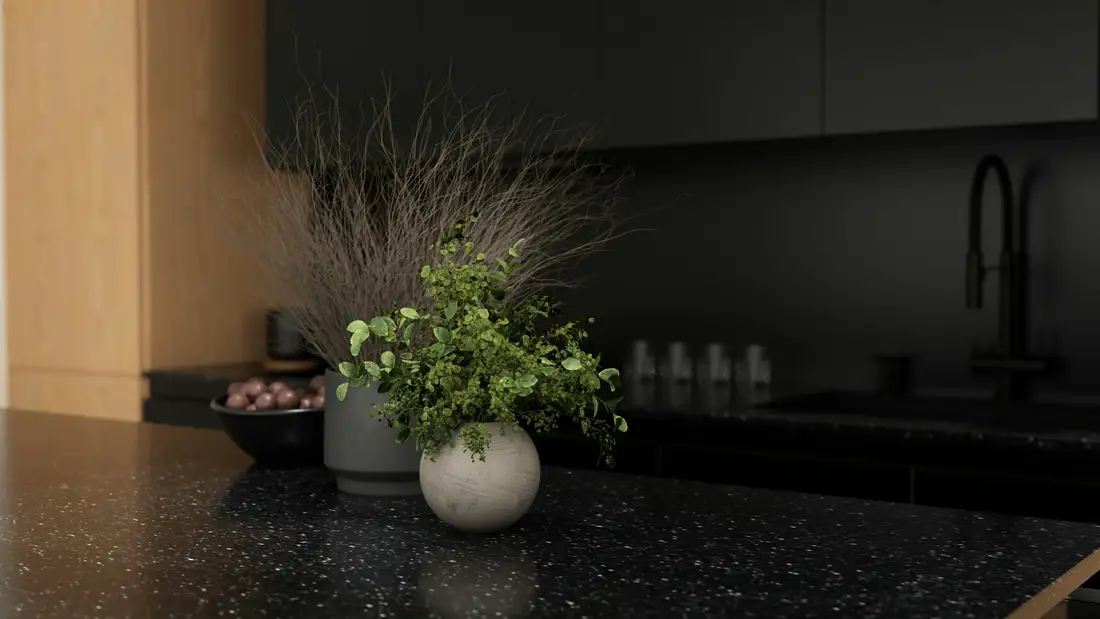A dark stone counter with a small plant and a ceramic bowl, low evening light