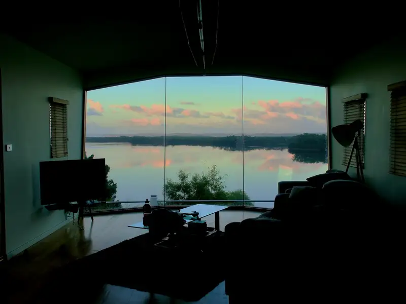 A dark den with a wide window onto the lake at dusk