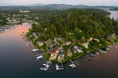 An aerial view at sunset of a wooded shoreline lined with private docks