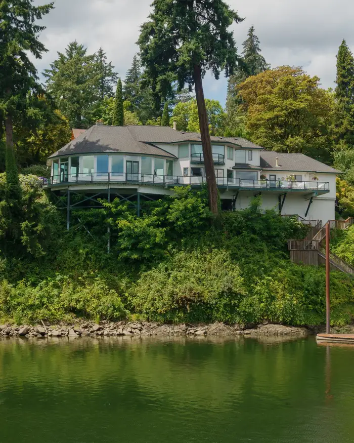 A house on a green bank above a lake, steps down to the water