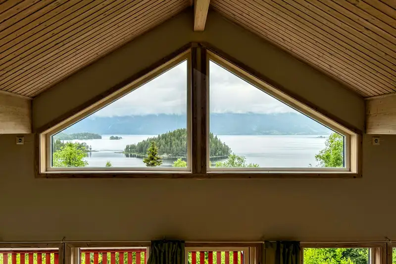 A gabled window framing a lake, islands and hills beyond