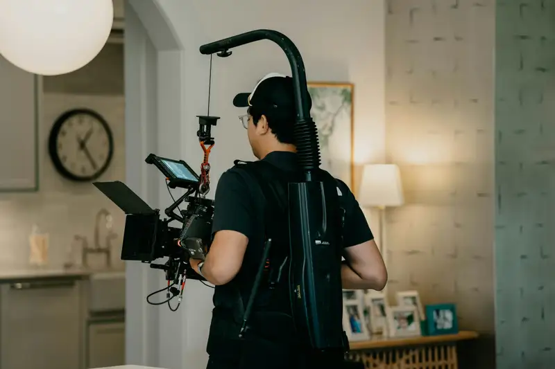 A camera operator with a stabilised rig filming a bright kitchen
