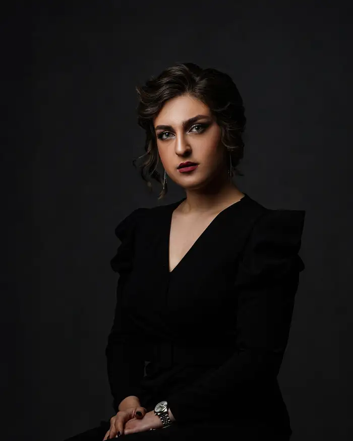 Sample portrait: a woman in a dark suit seated against a dark backdrop